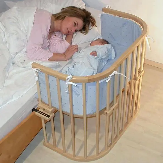 Majka sa bebom u krevecu pored bračnog kreveta